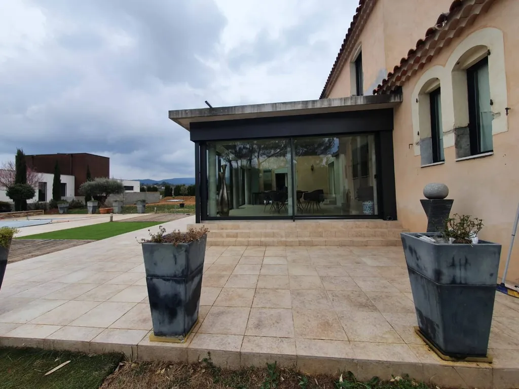 Installation d'une belle véranda en aluminium de la marque Technal de couleur noire près de Mimet