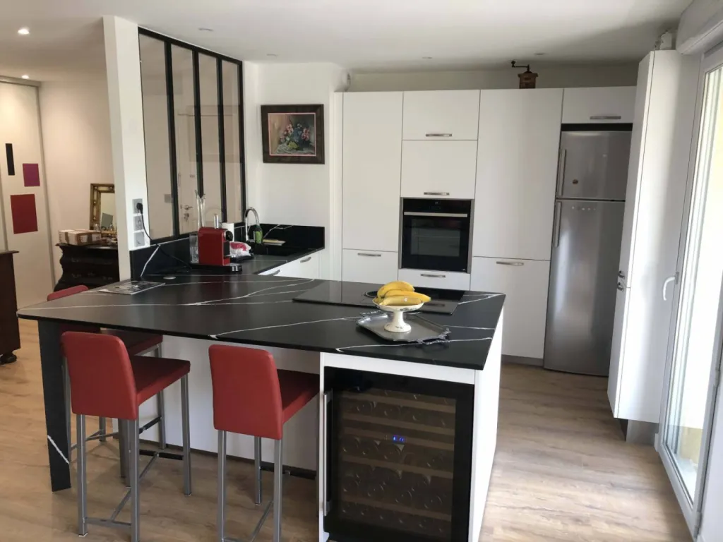 Création d’une cuisine blanche mat avec plan de travail en Silestone Eternal noir avec cave à vin intégrée dans un appartement aux Minimes