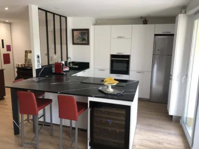 Création d’une cuisine blanche mat avec plan de travail en Silestone Eternal noir avec cave à vin intégrée dans un appartement aux Minimes