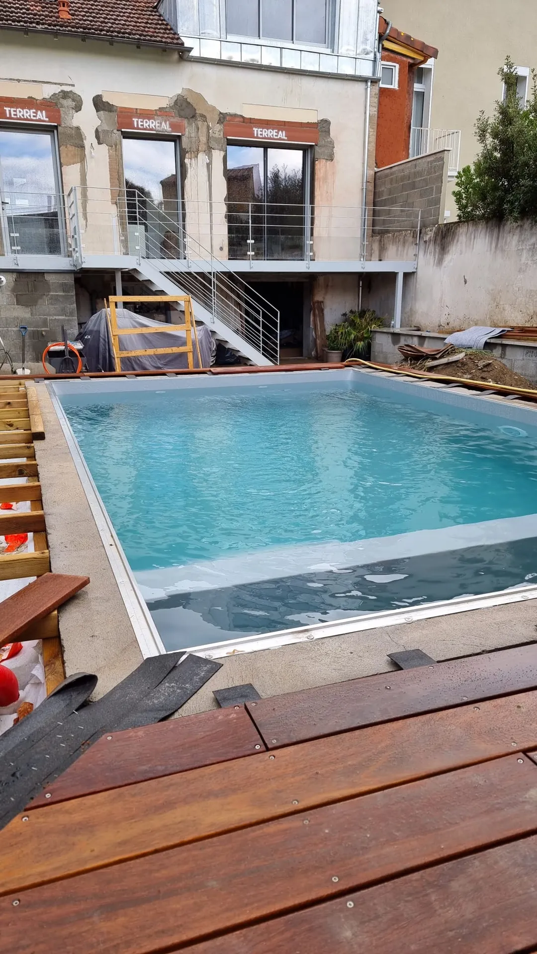 Une piscine traditionnelle intégrée au cœur d’un jardin toulousain sur mesure avec son volet roulant