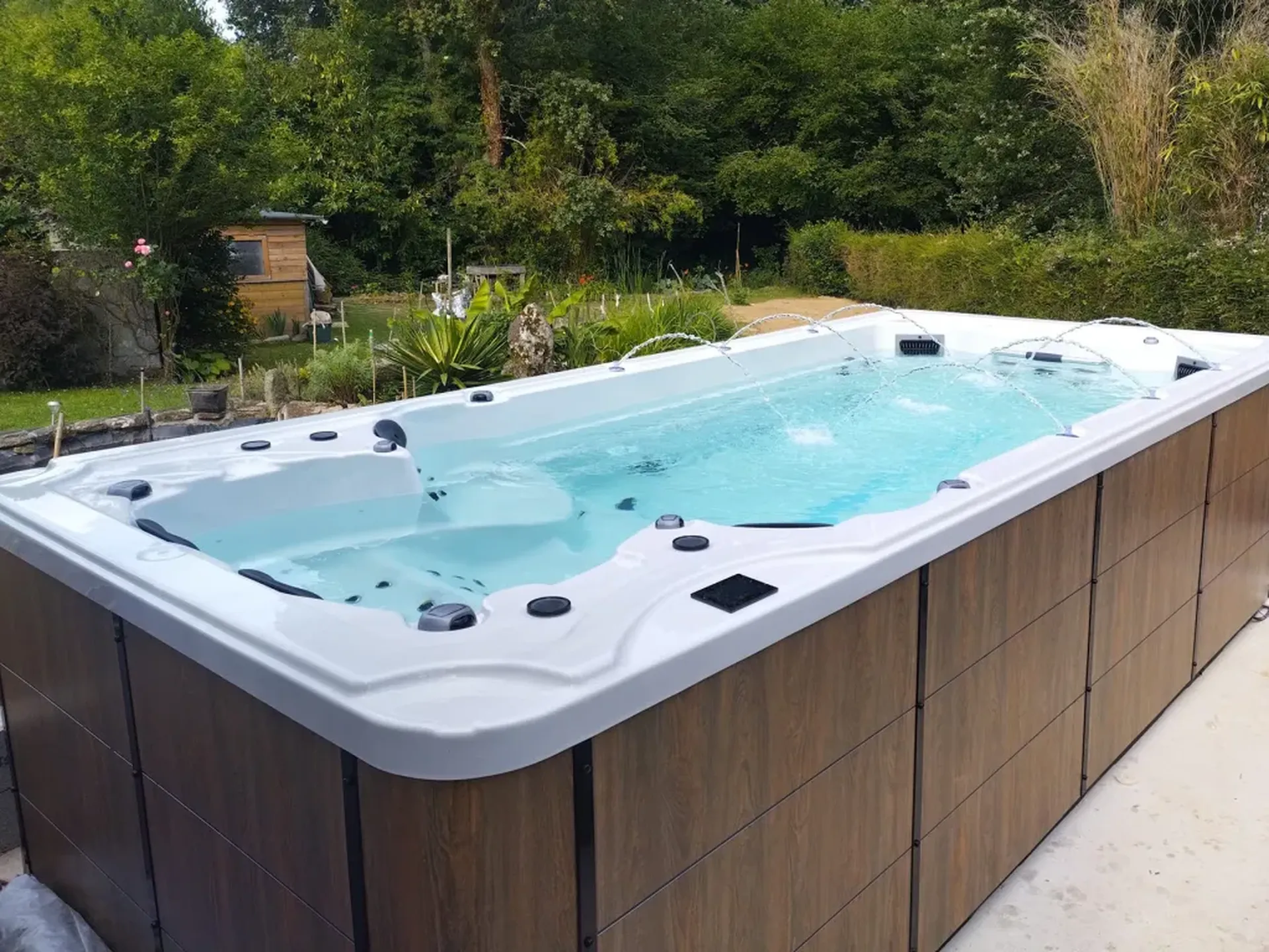 Spa de nage BE SPA Jade installé en extérieur avec finition bois, idéal pour sport et détente à domicile