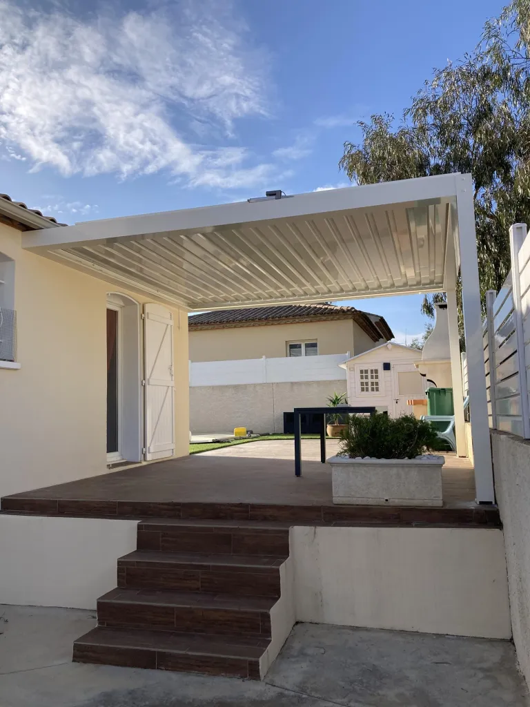 Pergola bioclimatique avec façade en lames motorisées RAL 9010 et coffres Sunworker à Lézignan-la-Cèbe dans l'Hérault 34