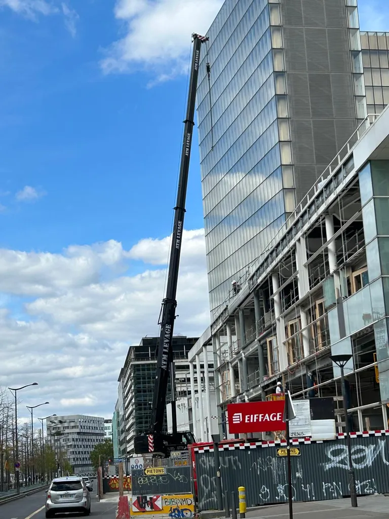 Louez une grue mobile à grande hauteur de flèche pour lever le long d'une tour de bureaux en construction à Paris, devis rapide