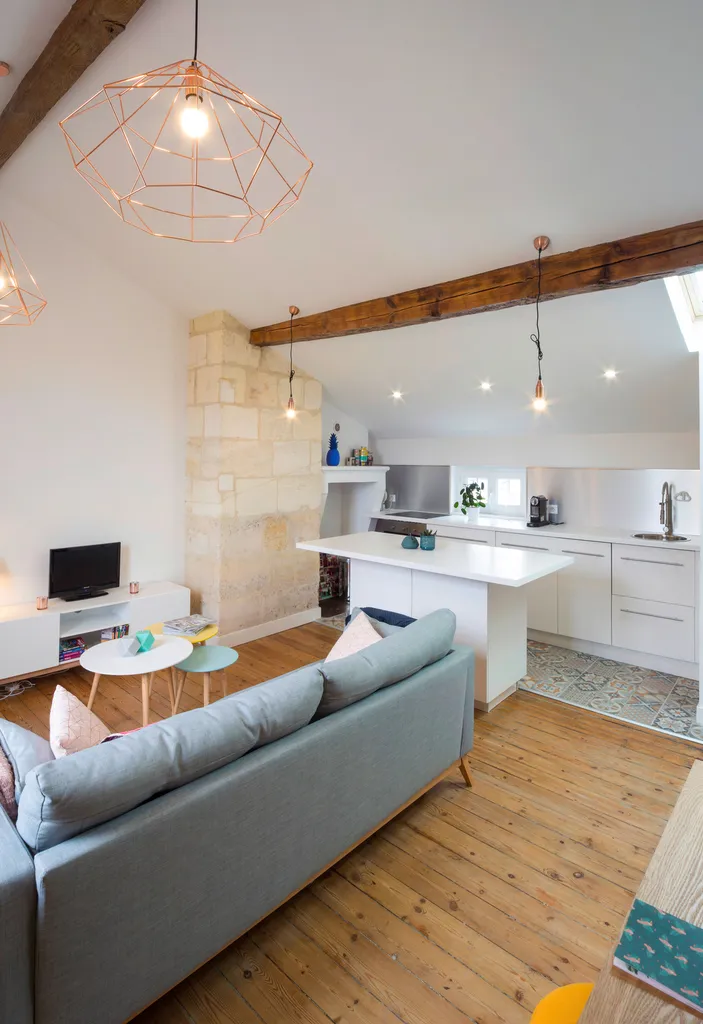 AKIKO ARCHITECTURE – Bordeaux Chartrons — Rénovation & réagencement sous combles Depuis la cuisine, le séjour se dévoile dans toute sa verticalité lumineuse, rythmée par des ouvertures au plafond. Le bleu structurant du bloc technique, associé aux matière