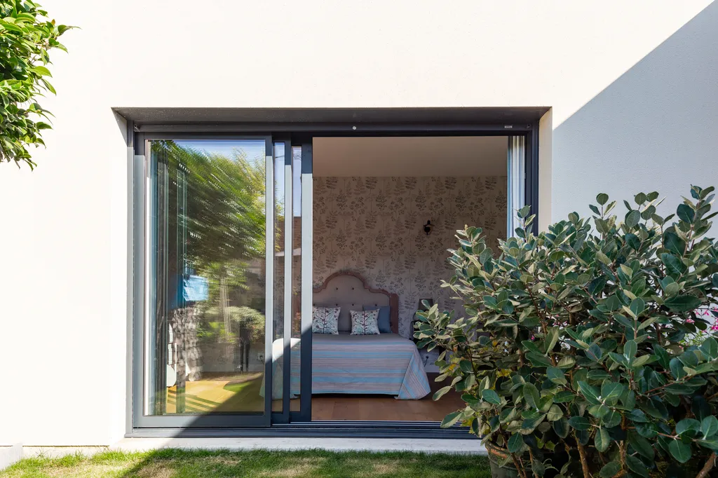 Chambre créée dans l’extension bois par AKIKO ARCHITECTURE à Bègles : une pièce lumineuse avec baie vitrée plein cadre, pensée pour une immersion permanente dans le jardin paysager