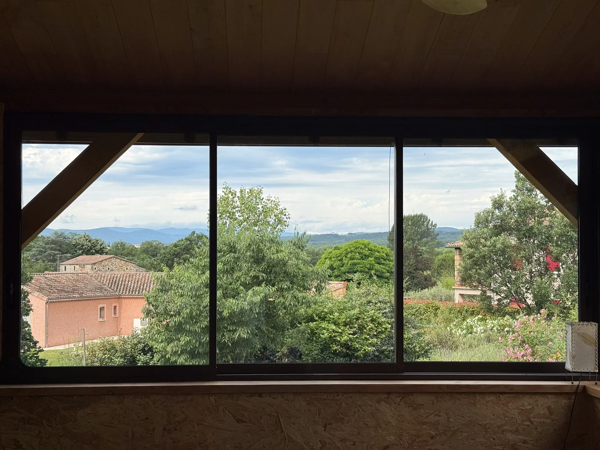 Fermeture d'une terrasse ardéchoise sous charpente bois avec de grands coulissants aluminium teinte rouille