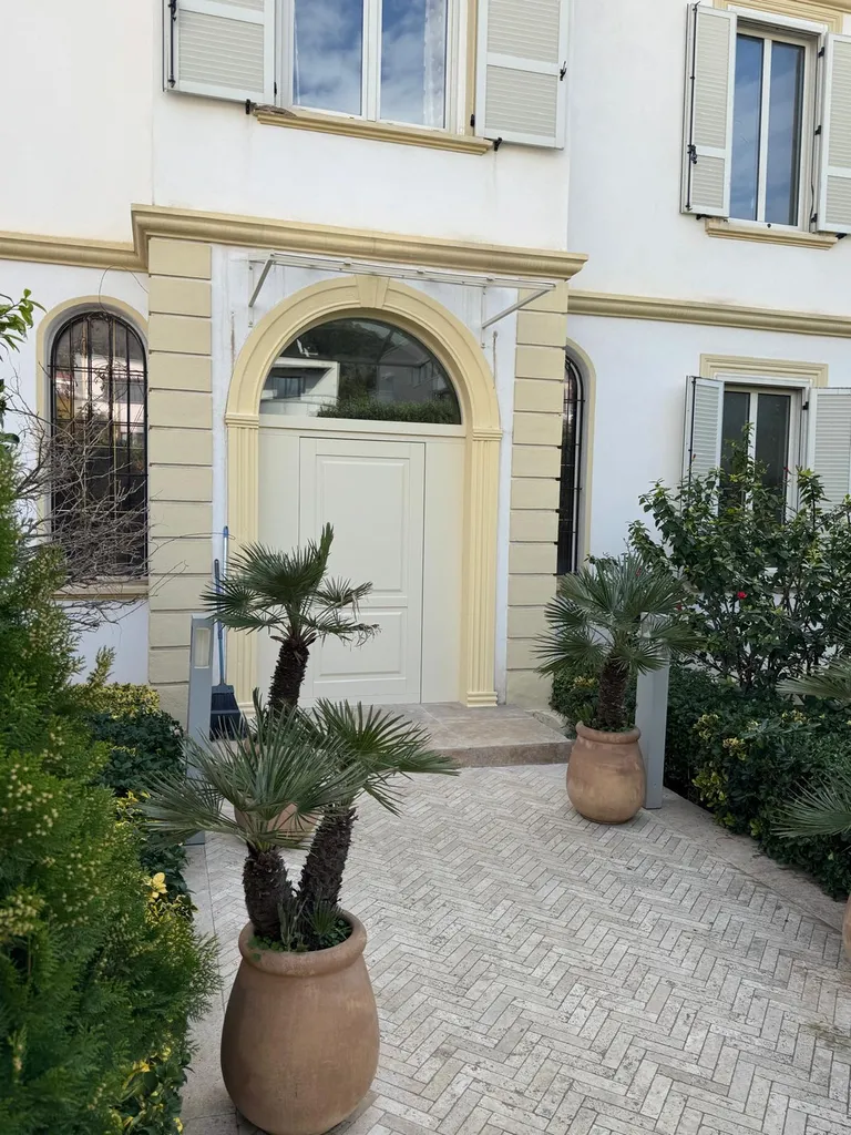 Rénovation d'entrée dans le Vieil Ajaccio : porte Silvelox Perseo laquée ivoire, marquise Ocler Azura et marche en travertin pour une façade retrouvée