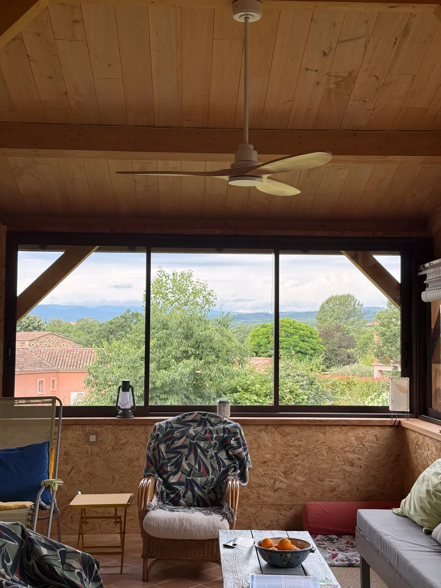 Fermeture d'une terrasse ardéchoise sous charpente bois avec de grands coulissants aluminium teinte rouille