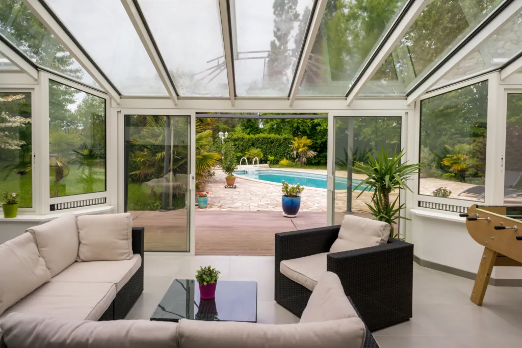 Réalisation d’une véranda de salon avec toiture vitrée à Ecully, design haut de gamme avec volet roulant intégré et stores sur mesure