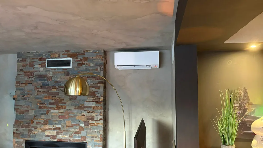 Installation de climatisation réversible Daikin Perfera dans un salon moderne avec mur en béton ciré à Villeneuve-lès-Avignon par CGF