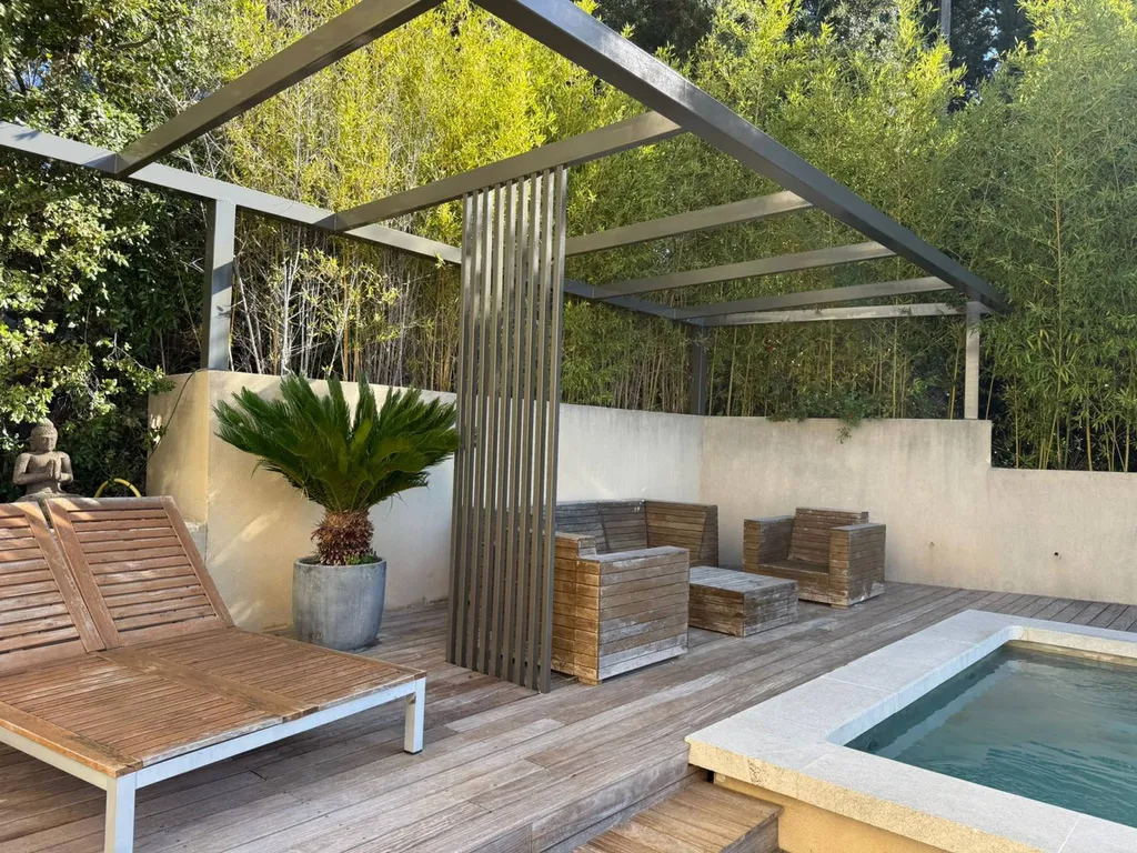 Pergola moderne sur terrasse bois avec salon d’extérieur et piscine – réalisation artisanale L’Atelier du Ferronnier.