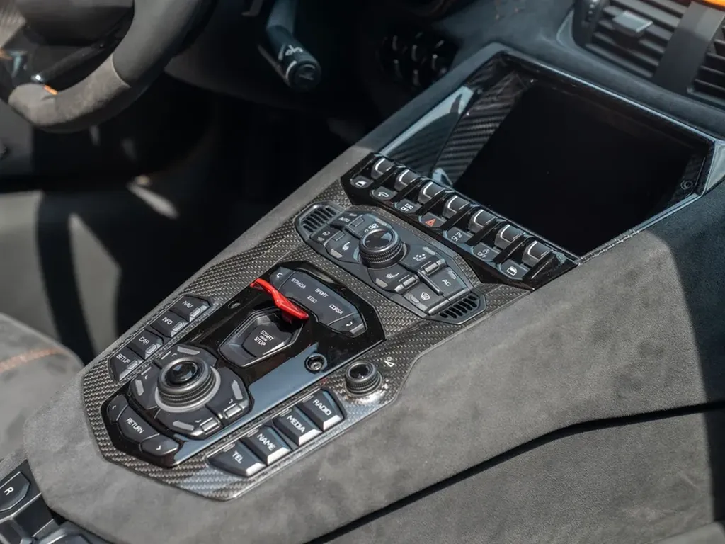 Console centrale en carbone de l’Aventador Ultimae, avec commandes de conduite, bouton Start/Stop rouge et finition Alcantara.