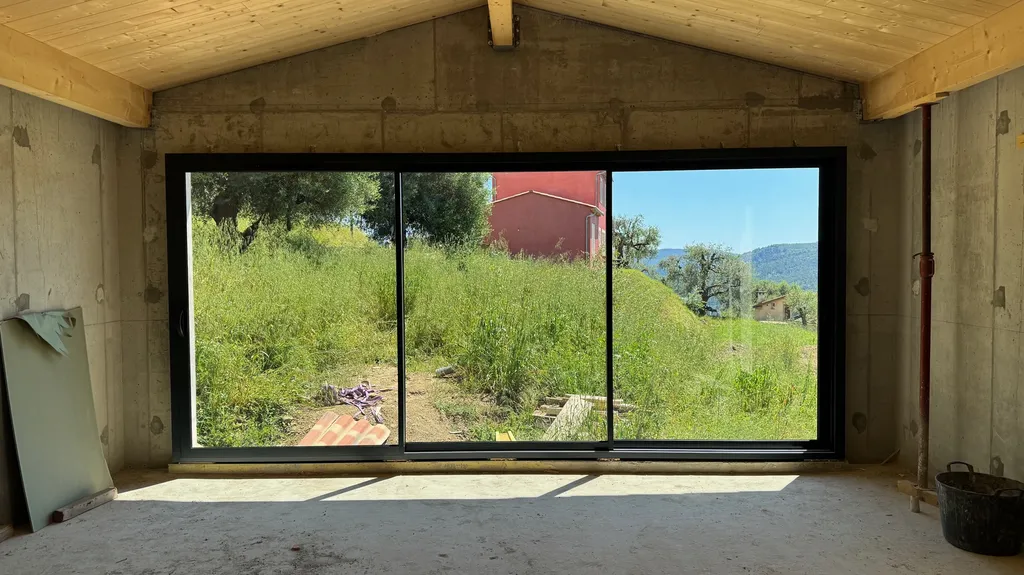 Installation de menuiseries mixtes avec coulissant aluminium SAPA Gris 7016, porte monobloc Sillage Evolution et fenêtres PVC Premio Plus à Contes dans les Alpes-Maritimes