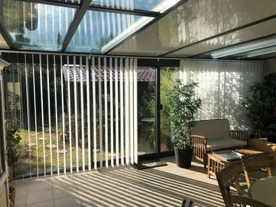 Installation de stores à bandes verticales sur la façade d'une véranda en aluminium TECHNAL à Puyricard