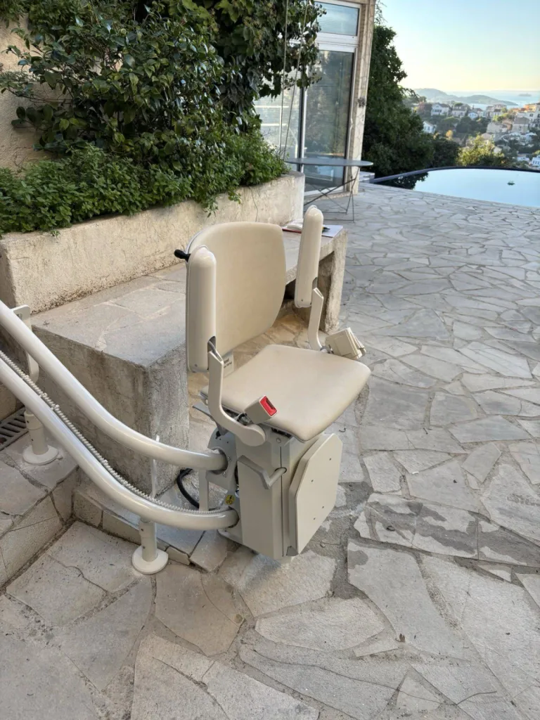 soleil couchant sur un fauteuil monte escalier OTOLIFT TWO spécifique pour l'extérieur installé à Marseille dans un escalier tournant