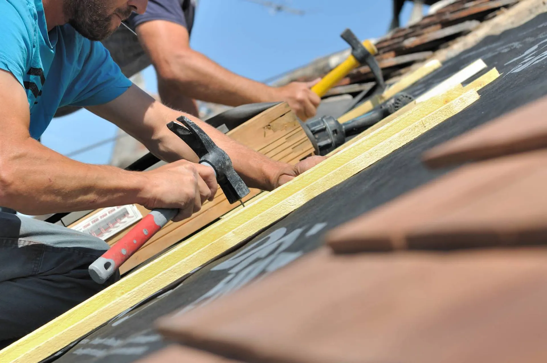 Artisan couvreur prenant des mesures sur une toiture en tuiles