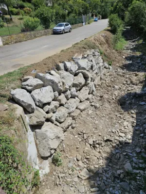 Entreprise de terrassement dans l'Ain pour Réalisation d'un enrochement brute avec grosses pierres pour soutenir le mur du fossé à l'entrée d'une maison à Saint-Genis-Pouilly