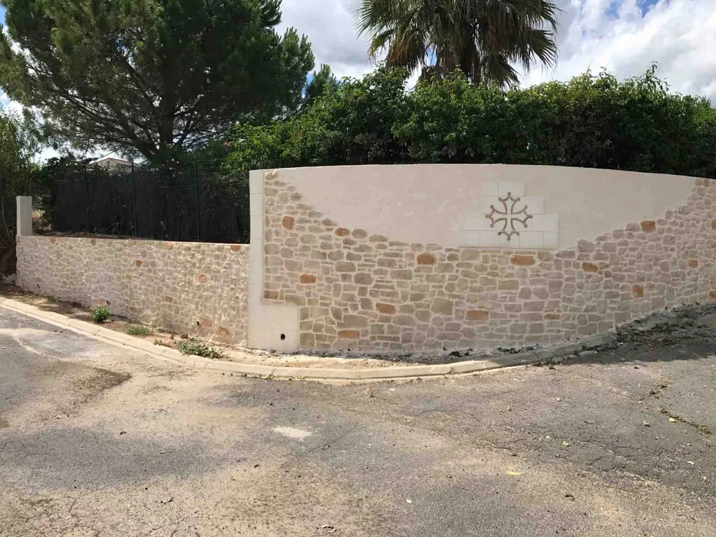 Clôture en pierre taillée avec cascade  et motif à Alignan du vent dans l'Hérault