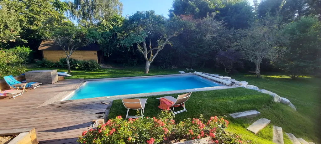 Piscine terrasse bois sur elevée enrochement autour - SAINT HYMMER