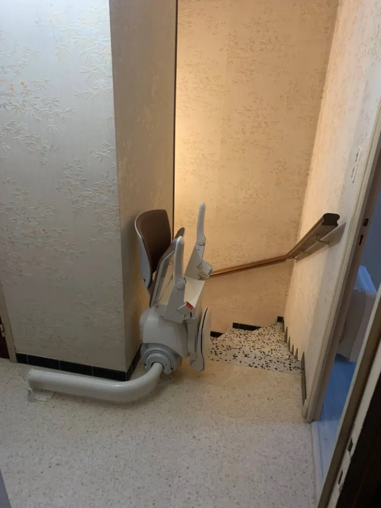 Stockage déporté et liberté de mouvement facilitée lorsque le siège est repliée après l'instalaltion de ce fauteuil monte-escalier monorail OTOLIFT Modul'Air en intérieur à six fours dans le Var entre Toulon & Marseille