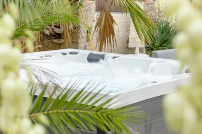 Livraison d'un jacuzzi haut de gamme 5 places à Nîmes, installé dans un jardin arboré pour une expérience de relaxation unique. - MCR Piscines et Spas - Gard