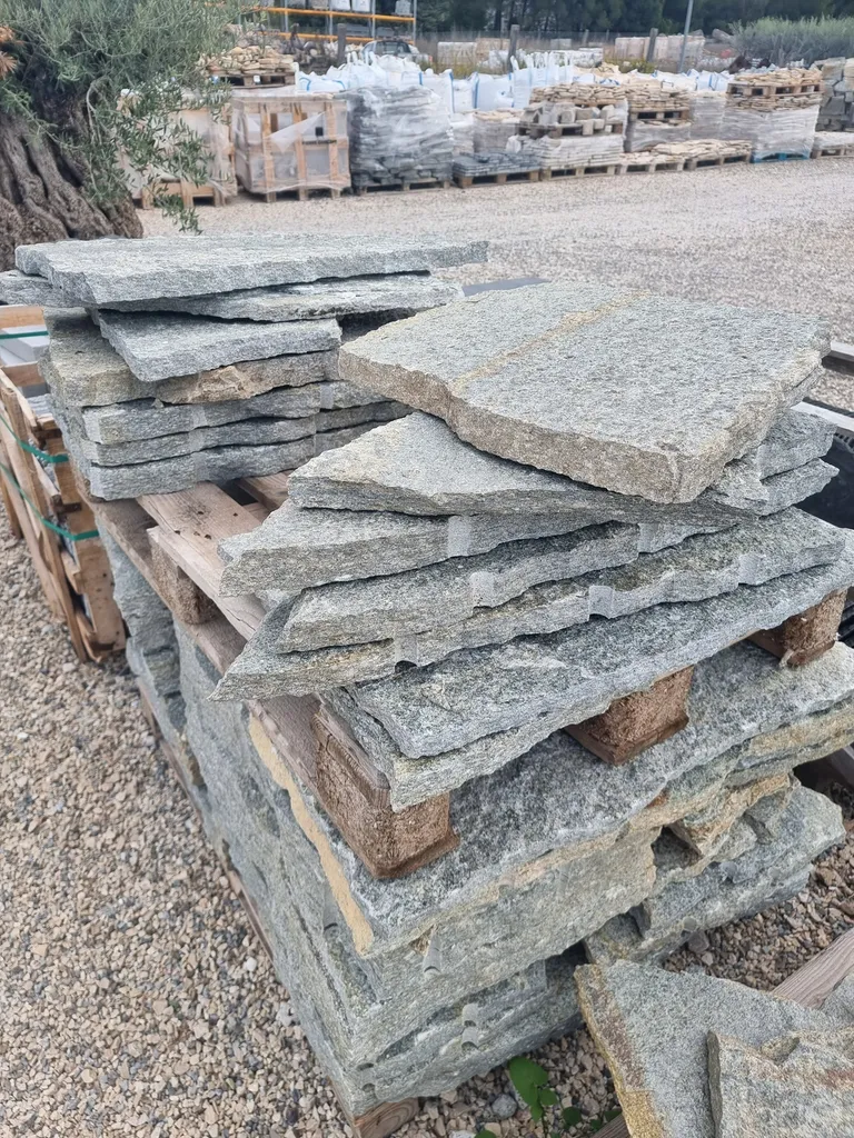Grandes pierres irrégulières de Luserne empilées sur palettes, pour un projet à Paris en Île-de-France.