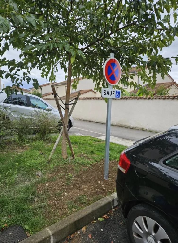 Pose d'un panneau de signalisation pour réserver le stationnement aux personnes en situation de handicap sur le parking d'une pharmacie à Décines à l'est de Lyon
