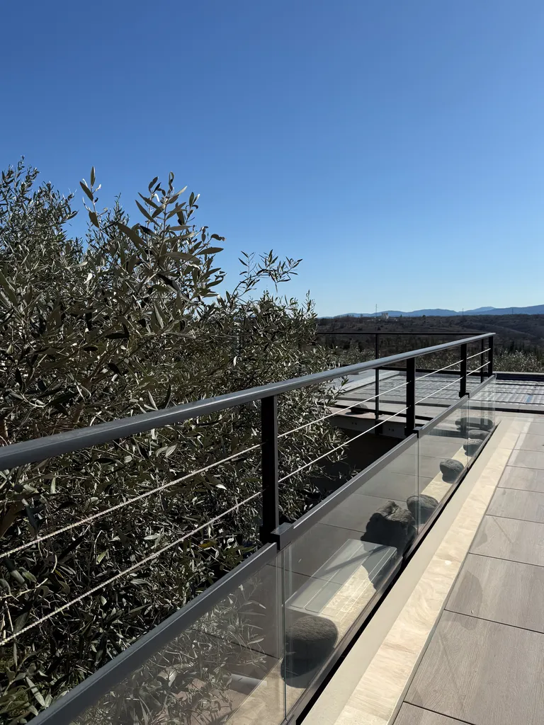 La finesse d’un garde-corps mêlant verre, câbles inox et aluminium pour ouvrir la terrasse sur le paysage
