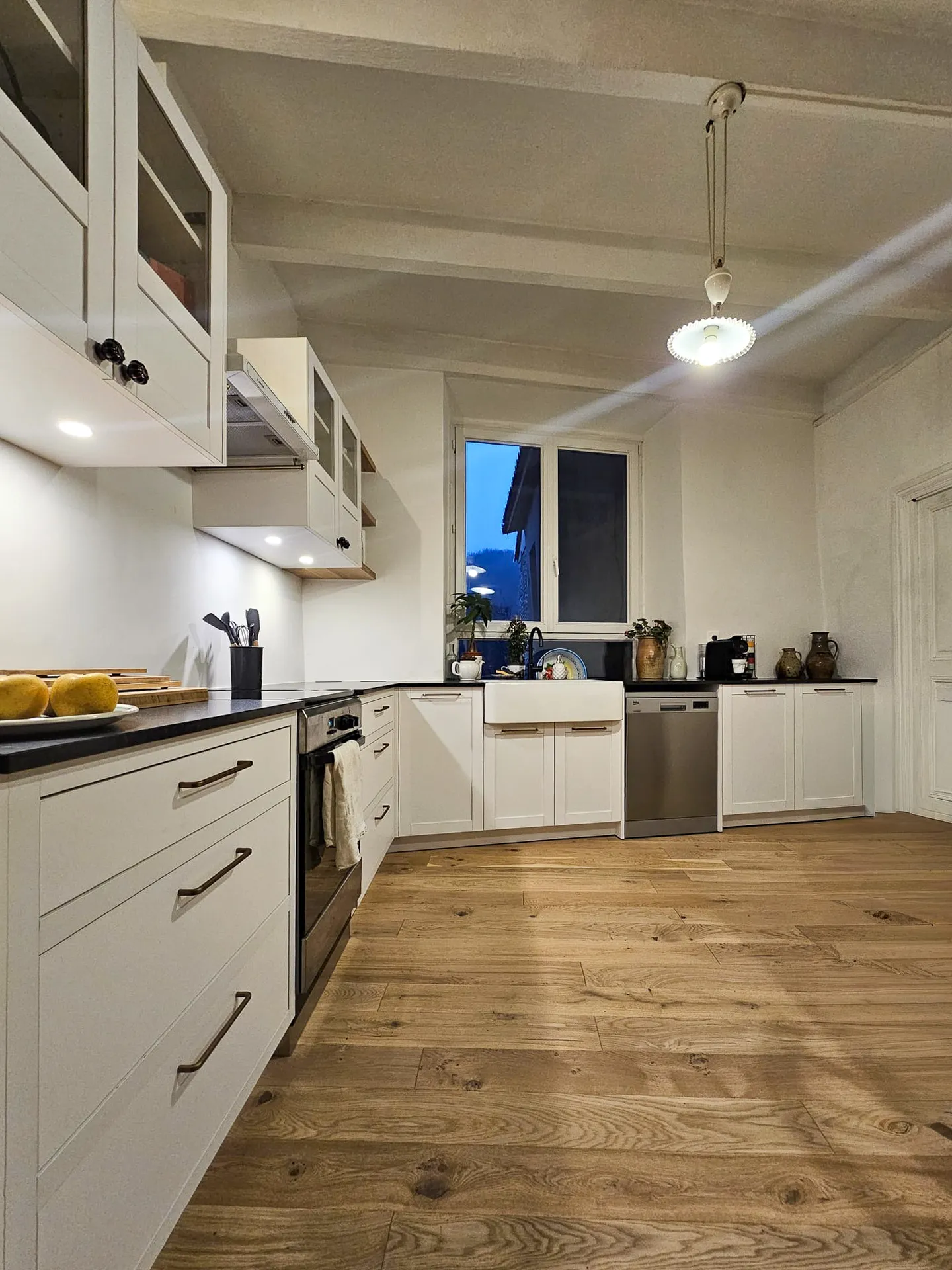 Cuisine sur mesure blanche et chêne à Vogüé : agencement en L, évier timbre d’office et finitions soignées
