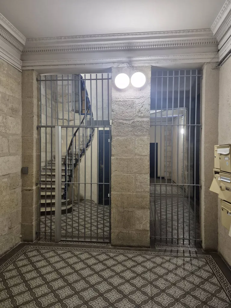 Grilles de protection métalliques sur mesure installées dans un hall d’immeuble ancien à Bordeaux.