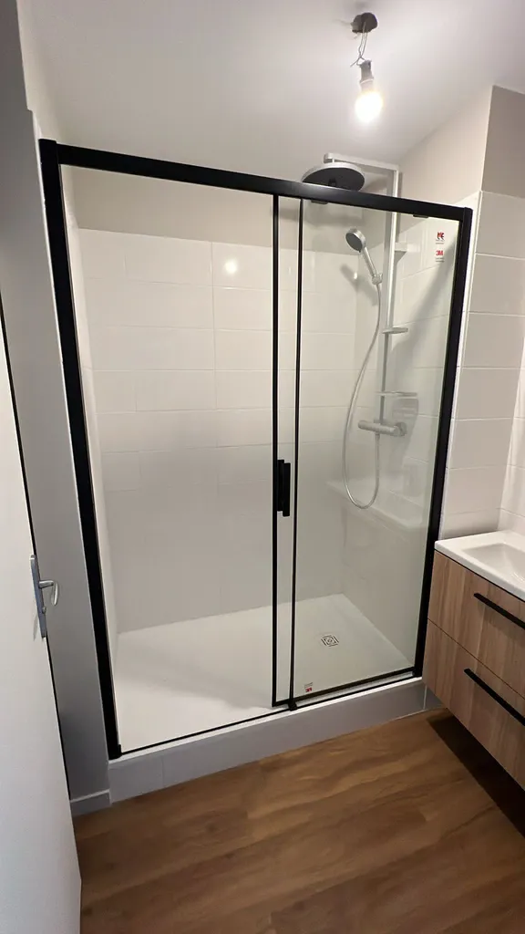 Plombier pour rénovation salle de douche Le Havre : remplacement meuble vasque et douche moderne avec porte coulissante