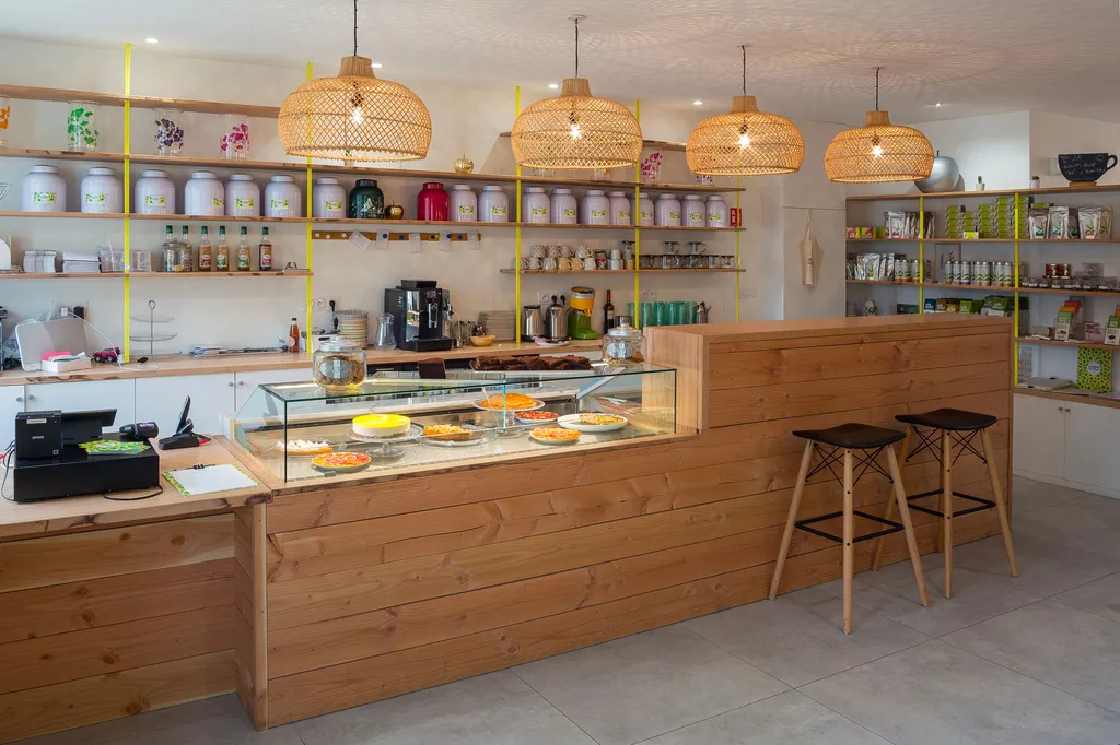 AKIKO ARCHITECTURE – Blanquefort / Taillan-Médoc – Rénovation & réagencement Le comptoir sur mesure, imaginé dans un bois clair chaleureux, devient la pièce maîtresse du lieu. Il organise les usages et guide le parcours client, tandis que les étagères ouv