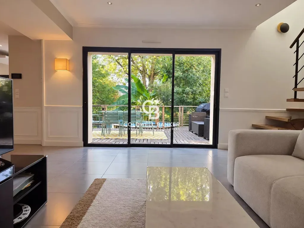 Salon ouvert sur la terrasse et le jardin par une grande baie vitrée, maison rénovée au Mans