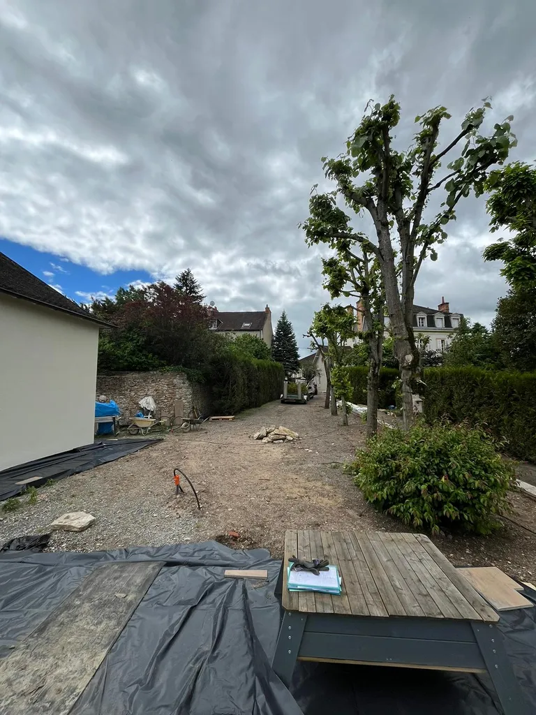 Aménagement paysager complet avec allée béton désactivé, gazon synthétique et massifs végétalisés sur mesure