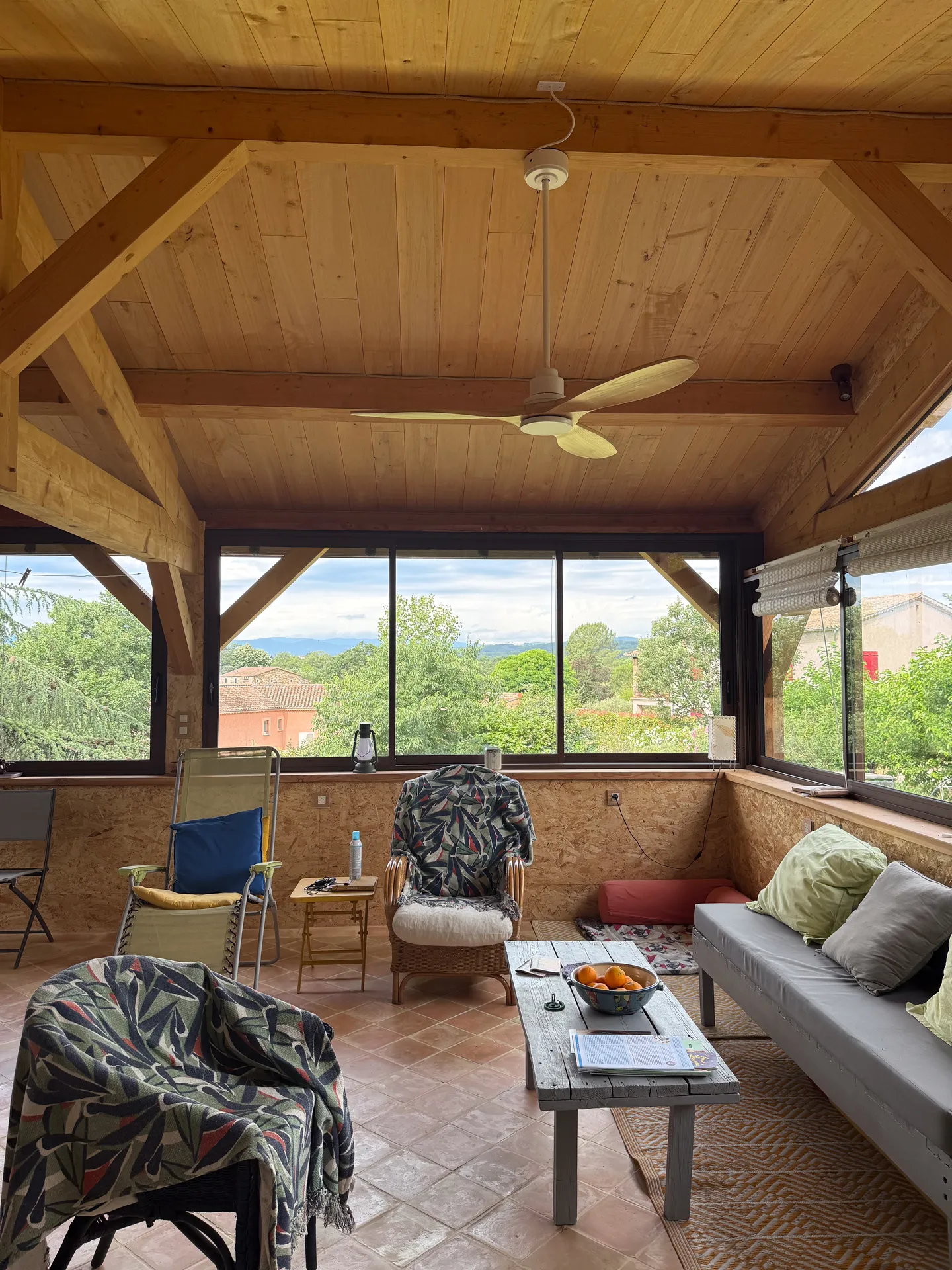 Fermeture d'une terrasse ardéchoise sous charpente bois avec de grands coulissants aluminium teinte rouille