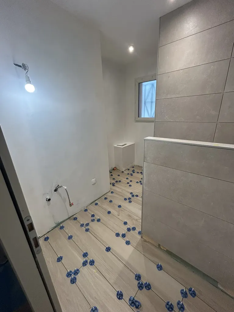 Pose de carrelage au sol lors de la rénovation de salle de bain à Villefranche-sur-Saône