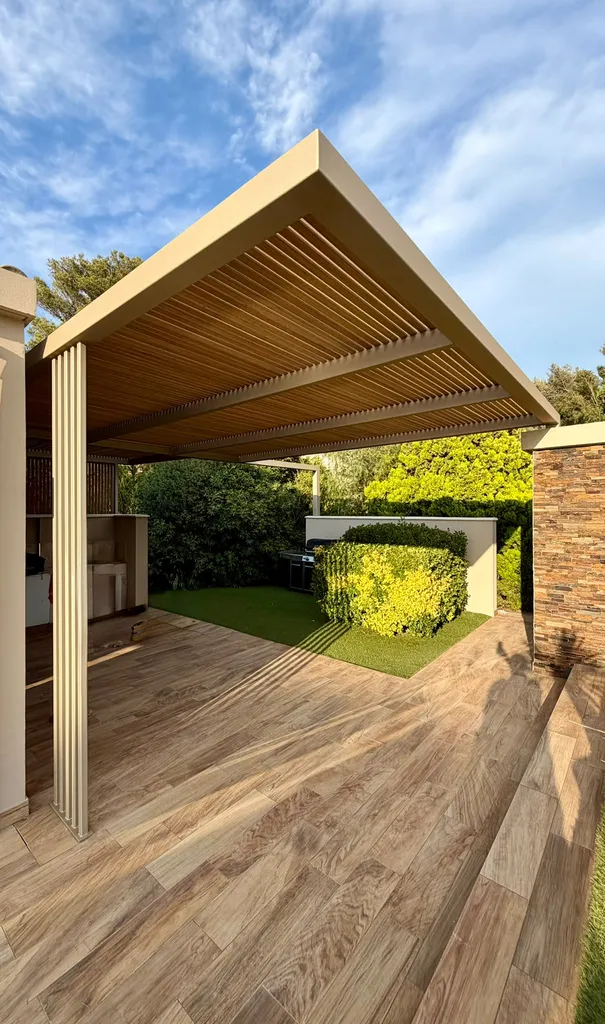 cuisine d'été installée sous une pergola en acier à sous-face à lames bois