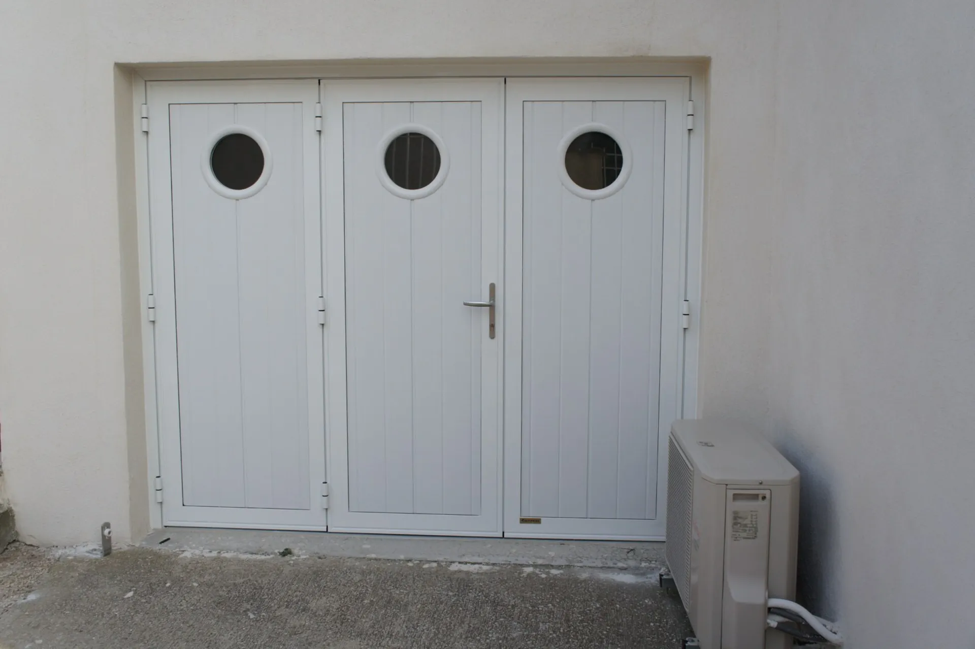 Porte de garage à trois battants blanche avec hublots ronds