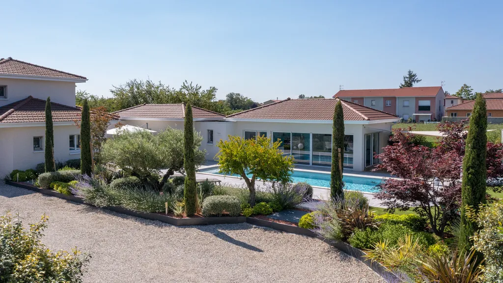 Aménagement paysager avec terrasse bois, gazon synthétique et voiles d’ombrage autour d’une piscine à Genas (69740)