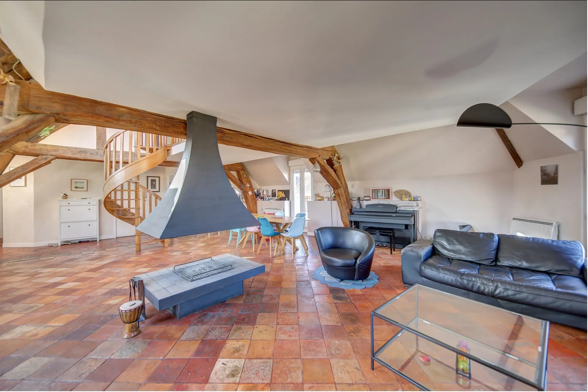 Vue salon lumière omniprésente cheminée centrale en vente chez Helix immobilier en exclusivité