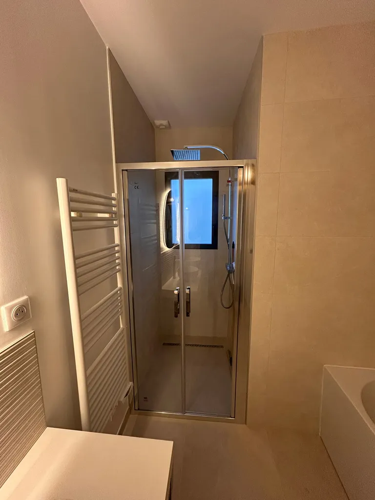 Zoom sur la douche à l'italienne moderne équipée d'une paroi vitrée à 2 portes battantes avec traitement anticalcaire