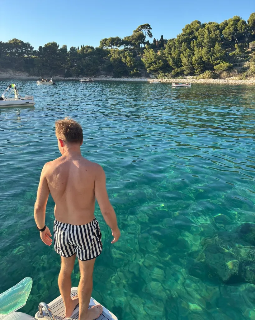 View from the boat of a family snorkelling in a sheltered cove, South of France