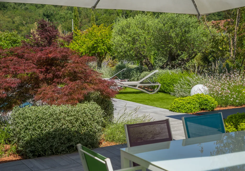Aménagement paysager avec terrasse bois, gazon synthétique et voiles d’ombrage autour d’une piscine à Genas (69740)