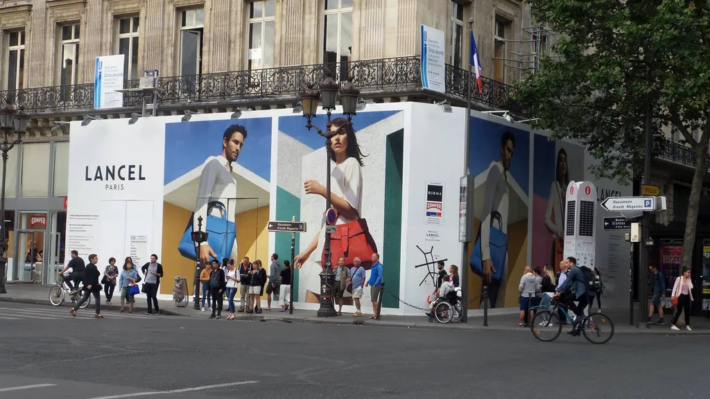 Pose d'une toile tendue sur la palissade bois de la boutique Lancel à Paris