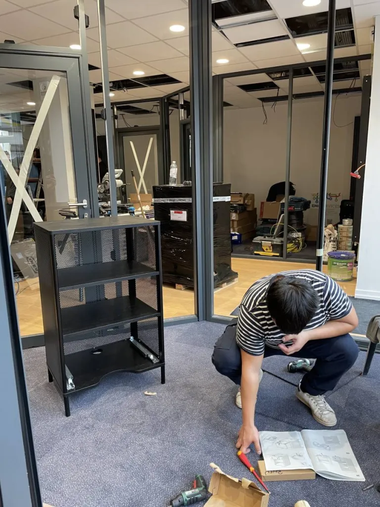 Salarié de l'entreprise Oben qui monte un meuble de rangement dans agence immobilière