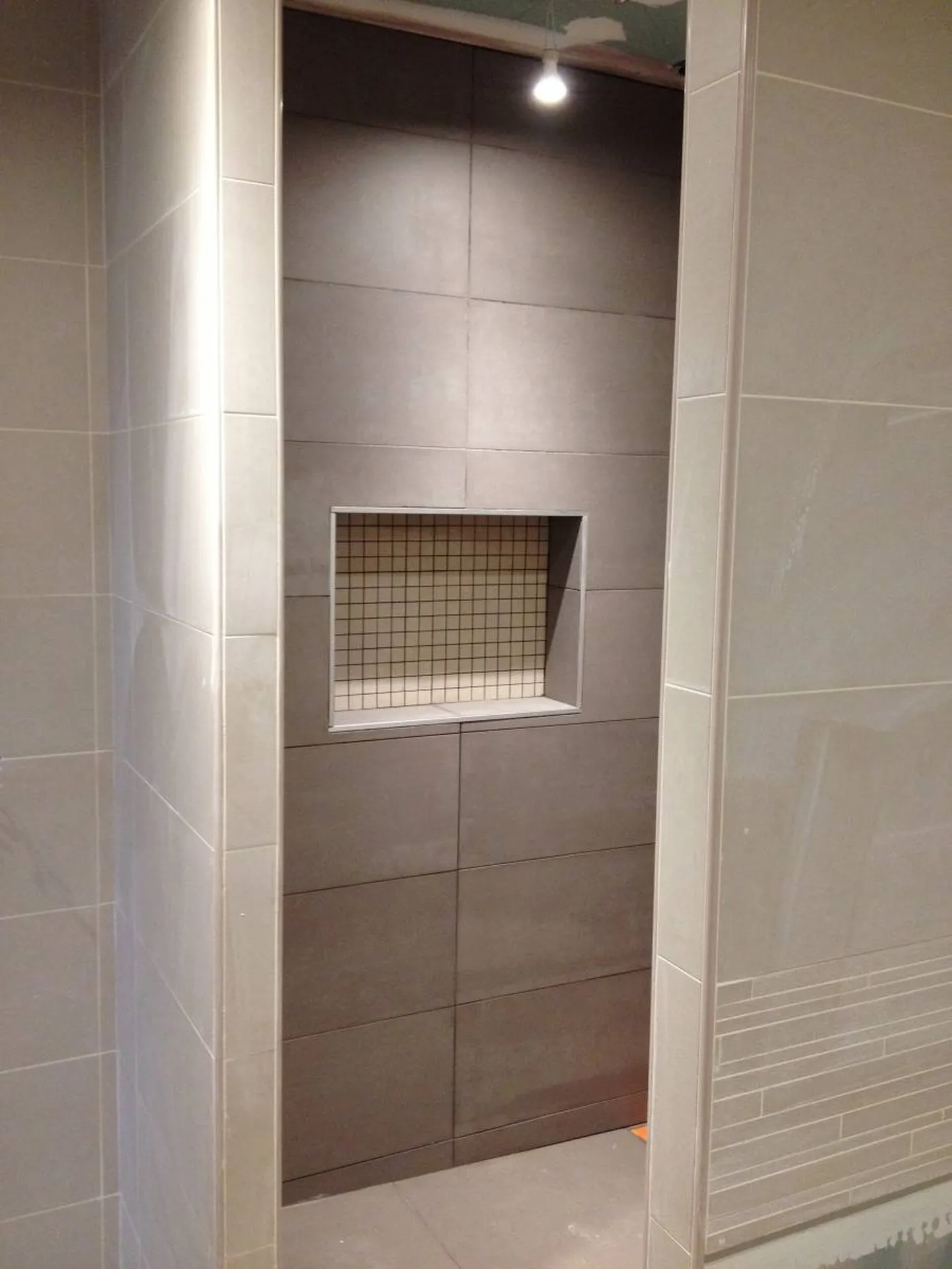 Pose du carrelage dans la douche avec niche intégrée pour les produits de toilette lors de la rénovation d’une salle de bain à Saint-Germain-au-Mont-d’Or (Rhône – 69)