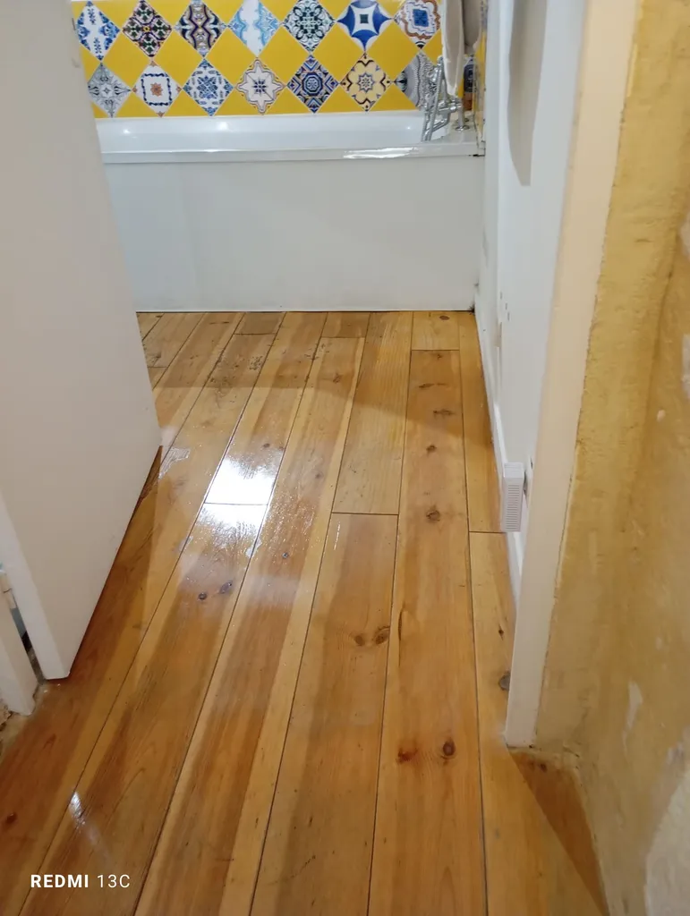 Nettoyage et entretien régulier du sol de votre maison à Bordeaux – parquet bois rénové et entretenu dans un couloir menant à une salle de bain