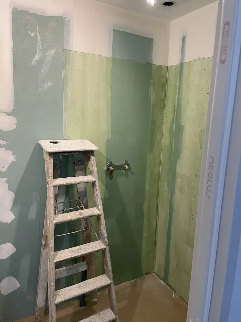 Application du SPEC (Système de Protection à l'Eau sous Carrelage) sur les parois de la douche. Une étape d'étanchéité liquide obligatoire avant la pose de la faïence pour éviter toute infiltration dans les murs en pierre