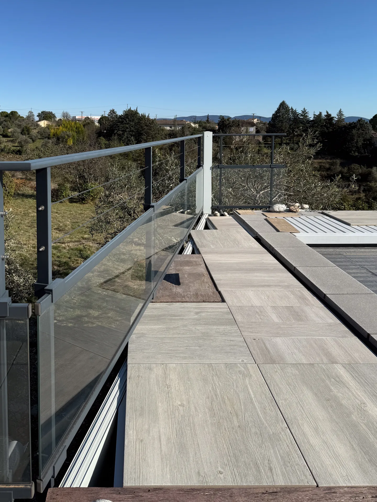 La finesse d’un garde-corps mêlant verre, câbles inox et aluminium pour ouvrir la terrasse sur le paysage