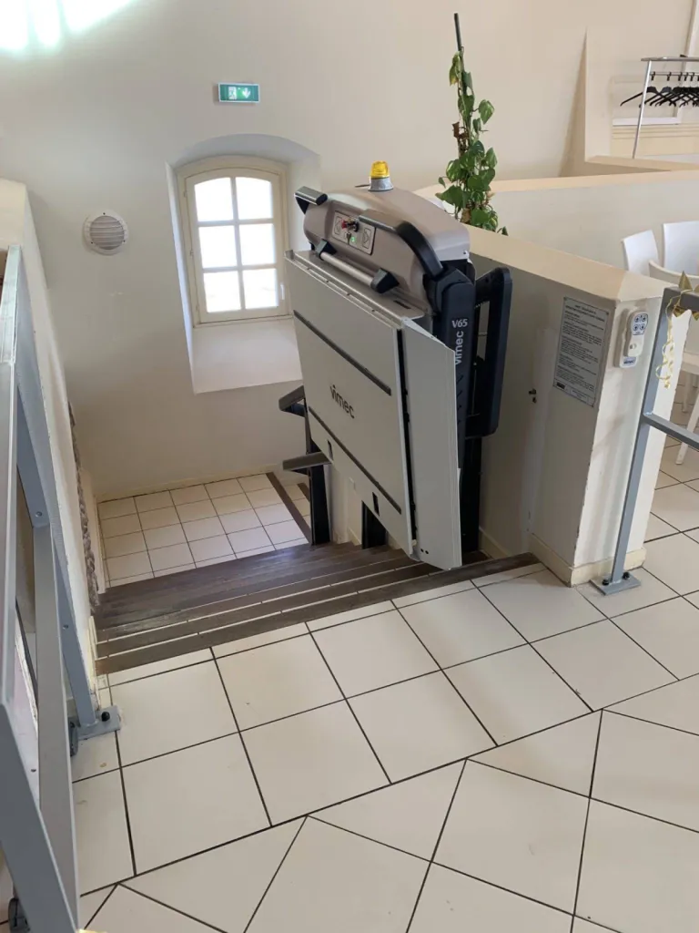 Espace libre laissé dans l'escalier avec cette plateforme oblique VIMEC V65 dans un escalier courbe au sein d'un ERP près d'Aix en Provence
